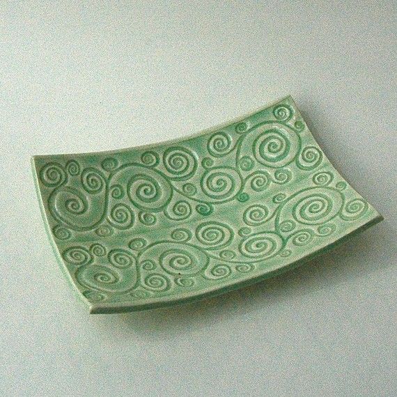 a green plate with swirls on it sitting on a white counter top next to a wall