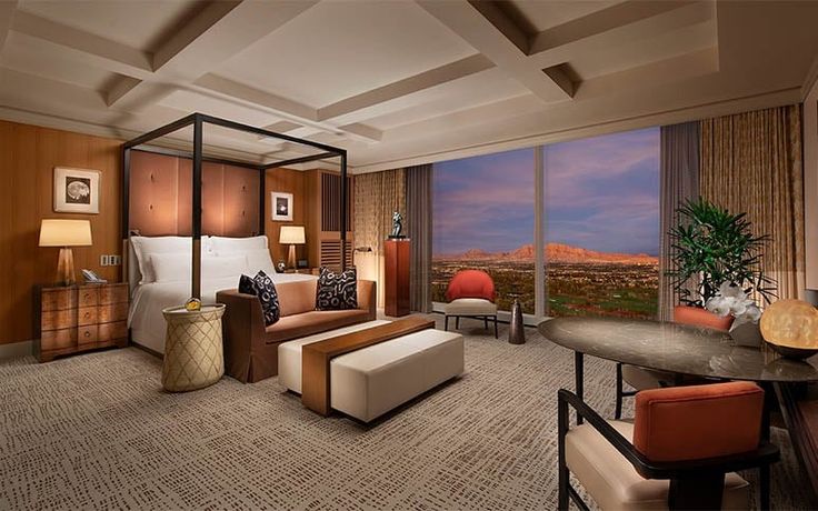 a bedroom with a large bed, desk and chairs in front of a window that looks out onto the desert