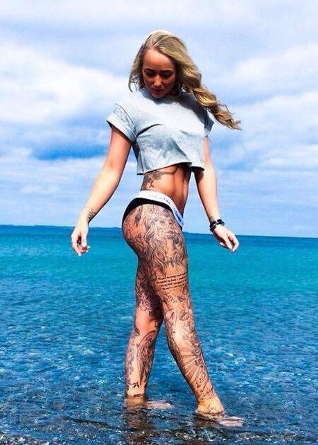 a woman standing in the water with tattoos on her body