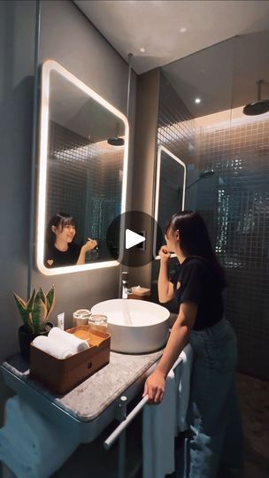 a woman standing in front of a bathroom mirror