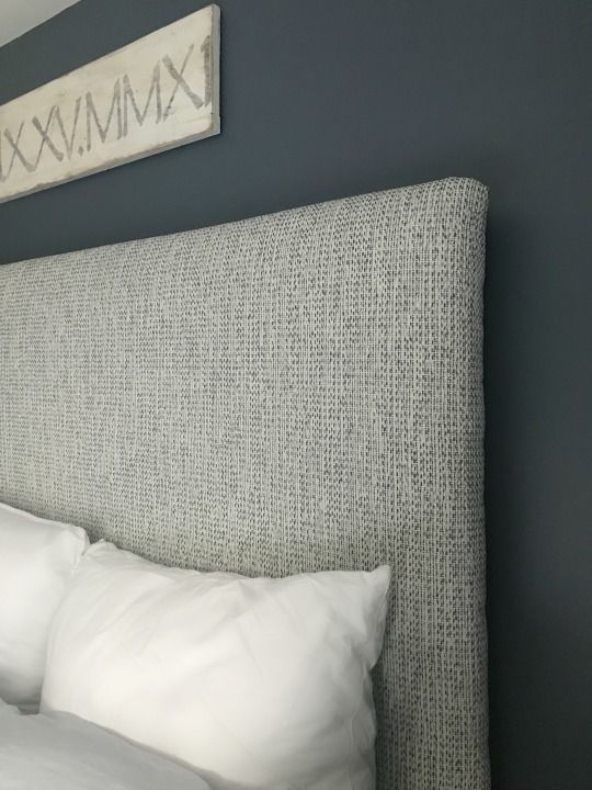 the headboard of a bed with white pillows and an x sign on the wall above it