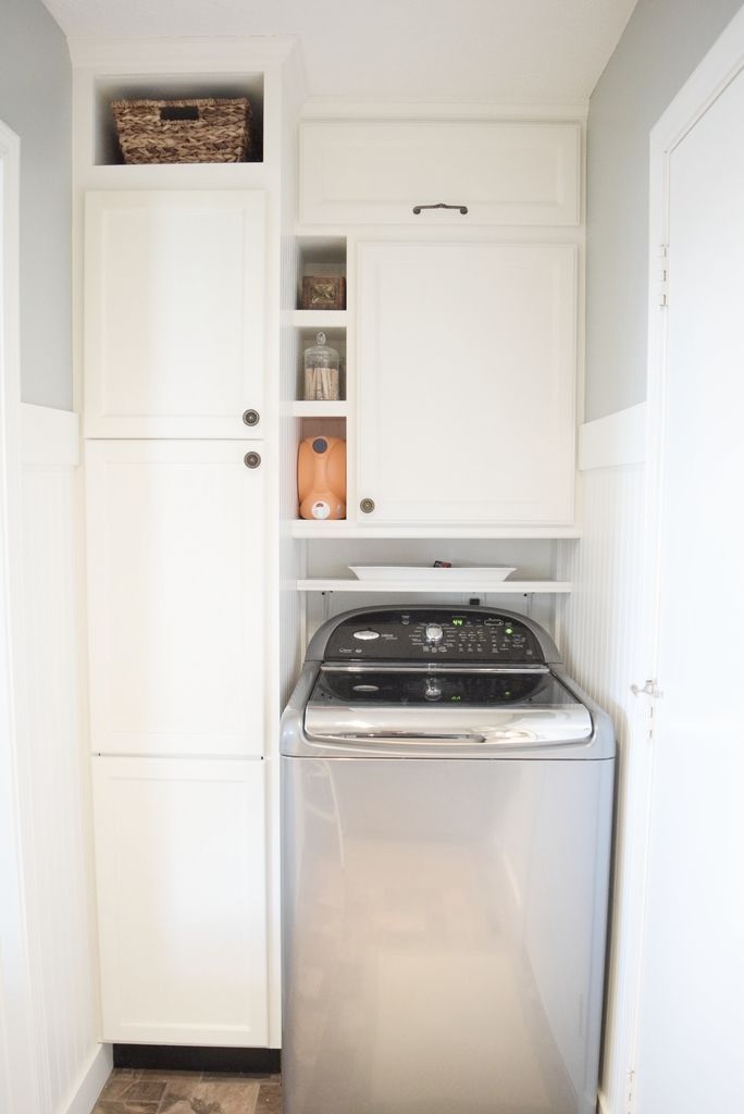 a white kitchen with a washer and dryer in the corner next to cabinets