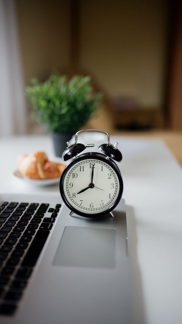 an alarm clock sitting on top of a laptop computer