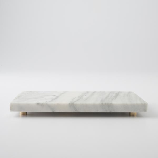 a white marble bench with gold legs on a plain surface, against a gray background