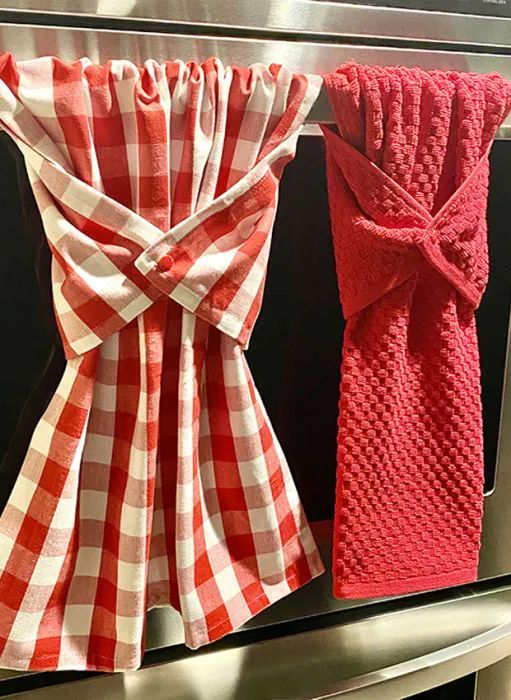 two red and white towels hanging on the side of an oven door, next to each other