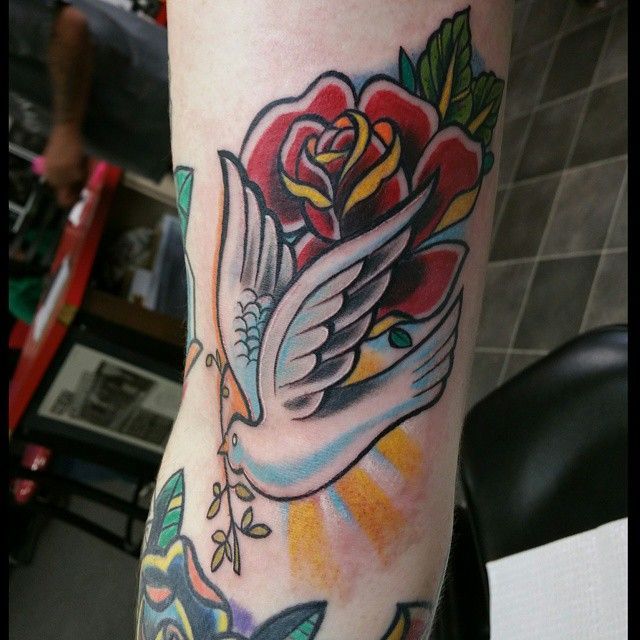 a tattoo on the arm of a woman with a rose and dove in it's center