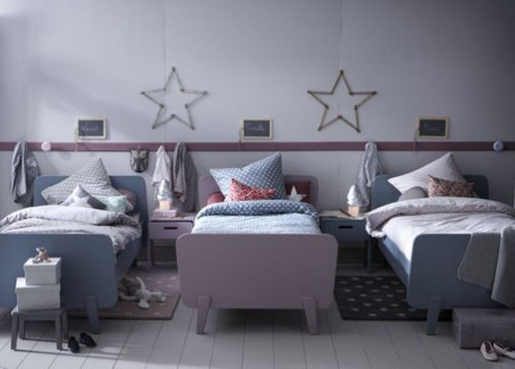 a room with two beds and some pillows on the bed, one has a pink footstool