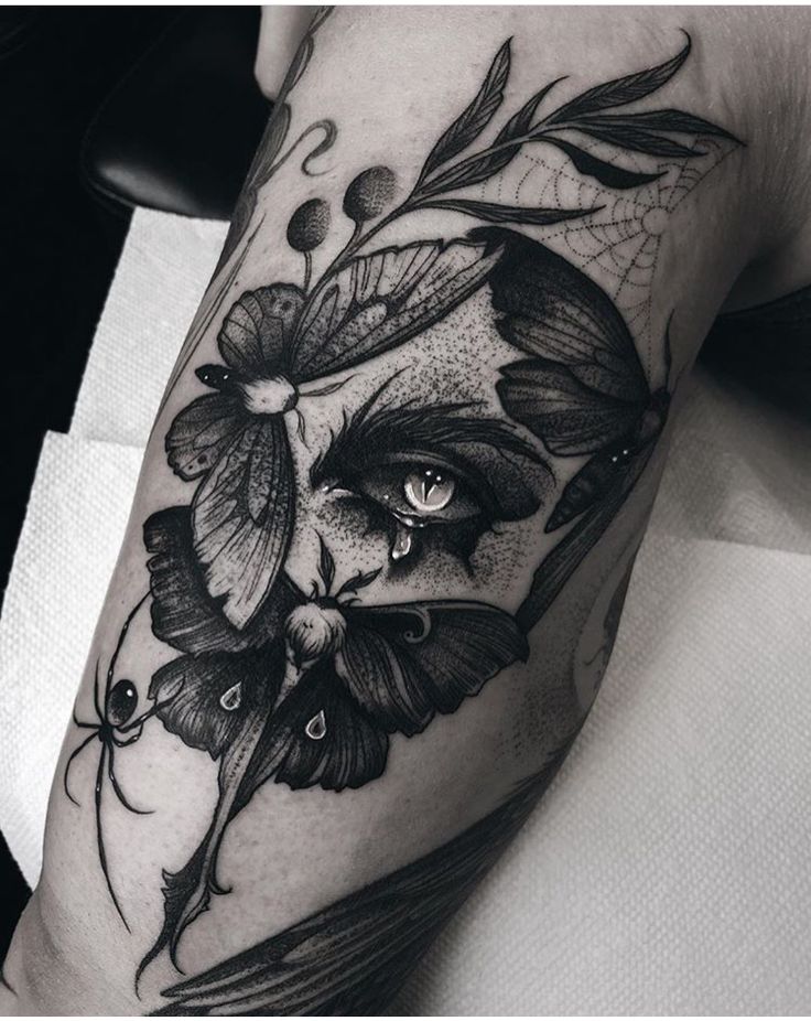 a black and white photo of a woman's arm with flowers, butterflies and leaves on it