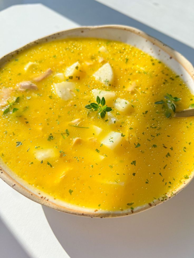 a white bowl filled with yellow soup on top of a table