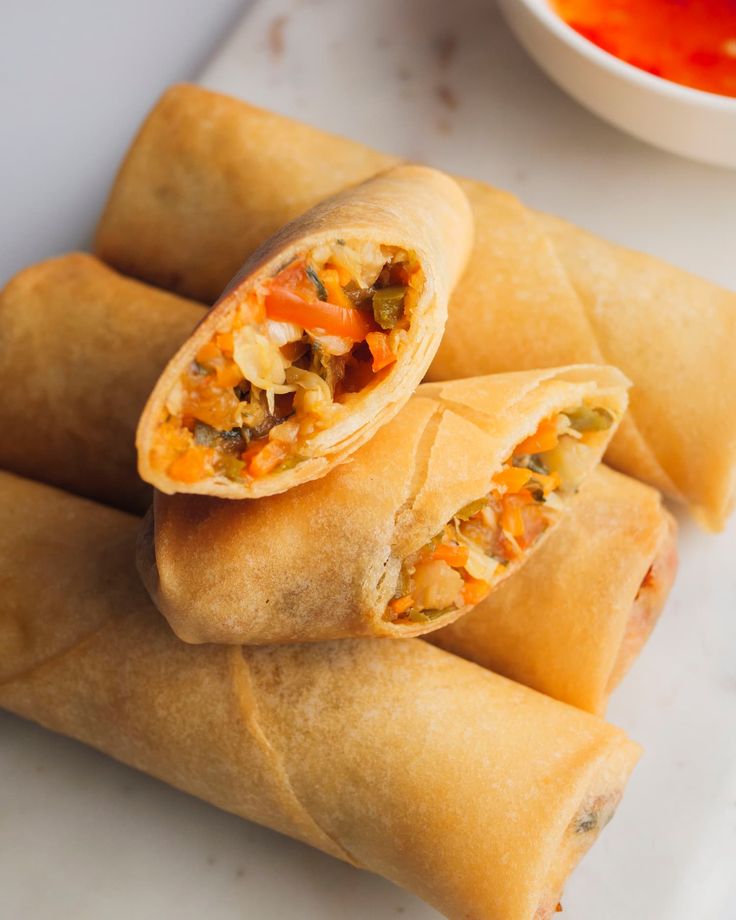 three vegetable spring rolls with dipping sauce on the side