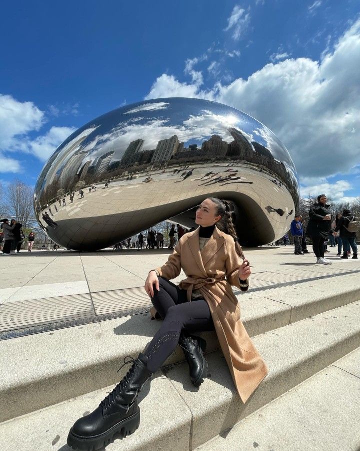 a woman is sitting on the steps in front of a large mirror ball, with her legs crossed