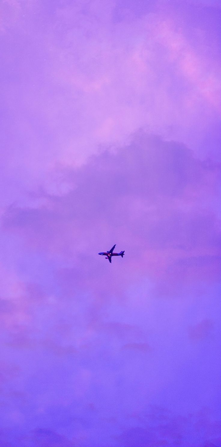 an airplane is flying in the purple sky