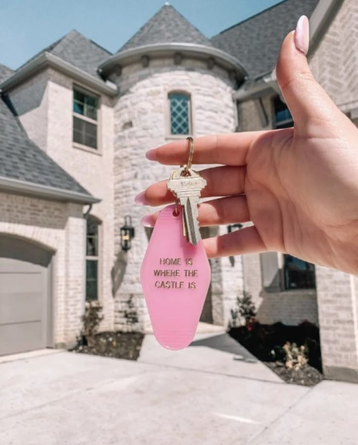 a person holding a pink key in front of a house