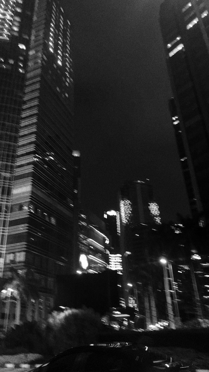 a black and white photo of some very tall buildings in the city at night time