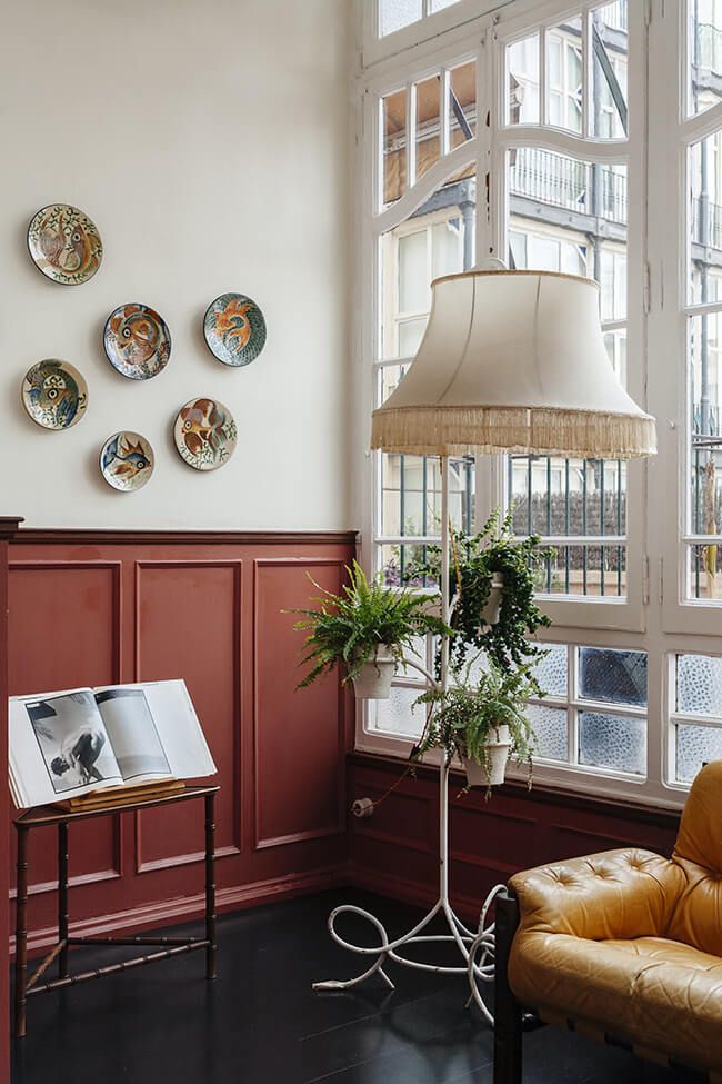 a chair and table in a room with plates on the wall behind it, along with a lamp