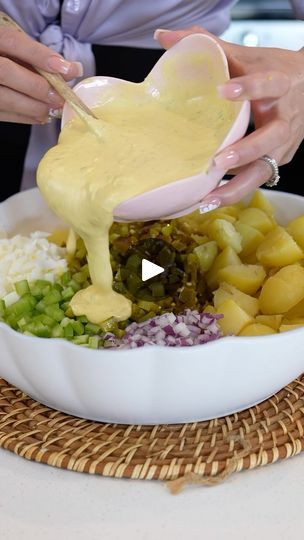 a person pouring dressing into a bowl filled with food