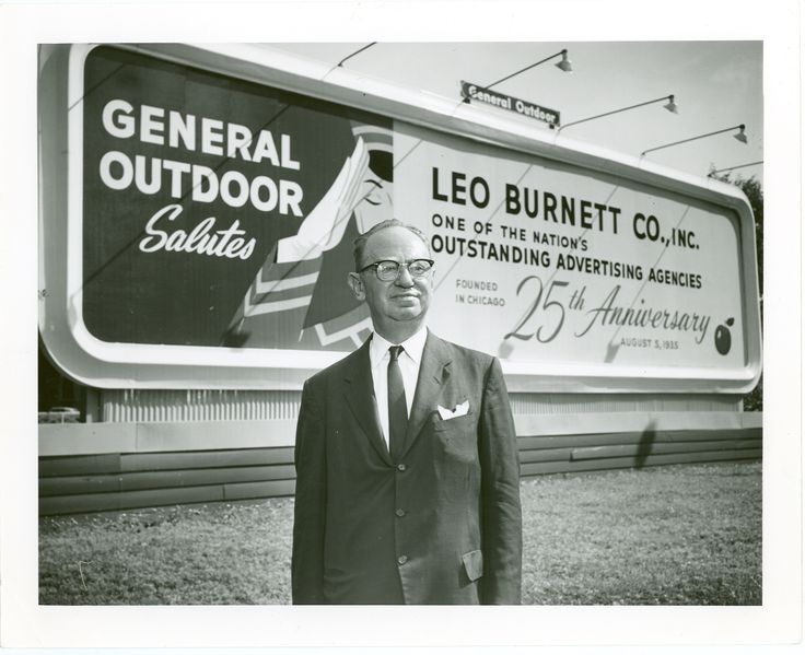 an old photo of a man standing in front of a sign