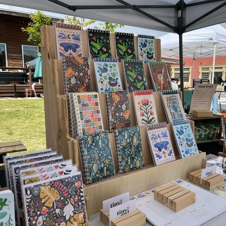 many cards are on display under a tent at an outdoor art show in the park