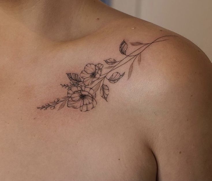 a woman's chest with flowers and leaves tattoo on her left side breast area