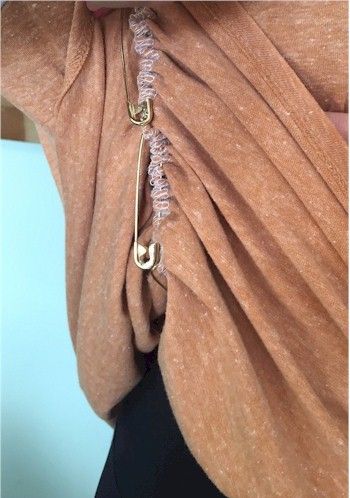 the back of a woman's shirt with an open neck and gold rings on it