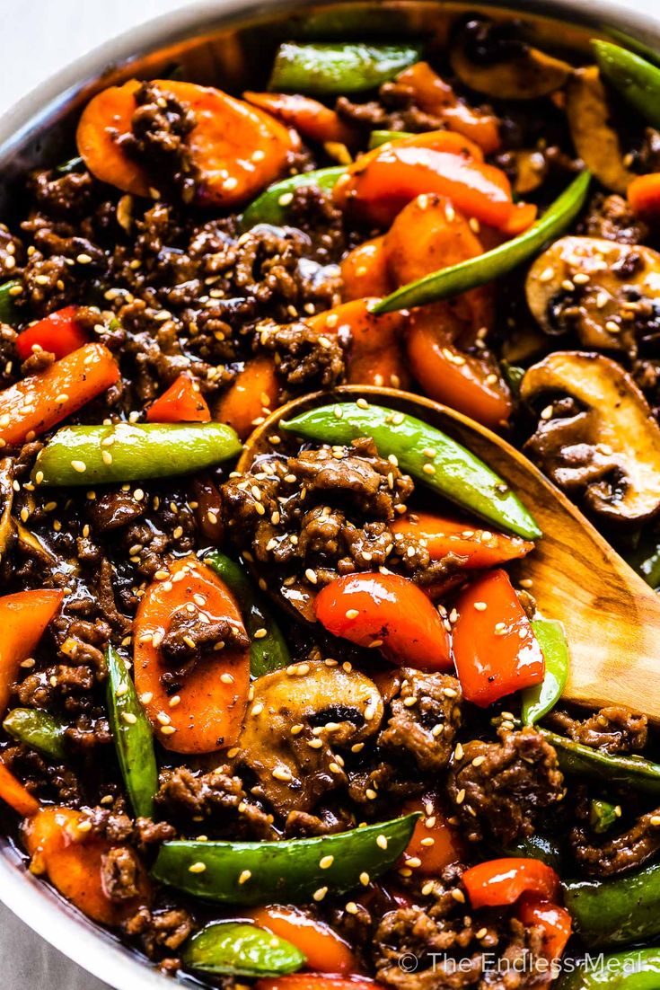 a skillet filled with ground beef, peppers and carrots on top of a table