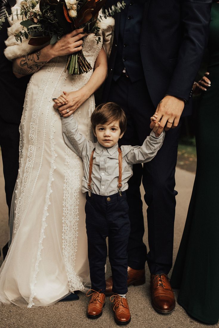 a little boy standing next to his mom and dad