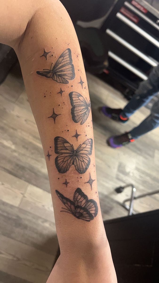 a woman's arm with butterflies and stars tattooed on the back of her leg