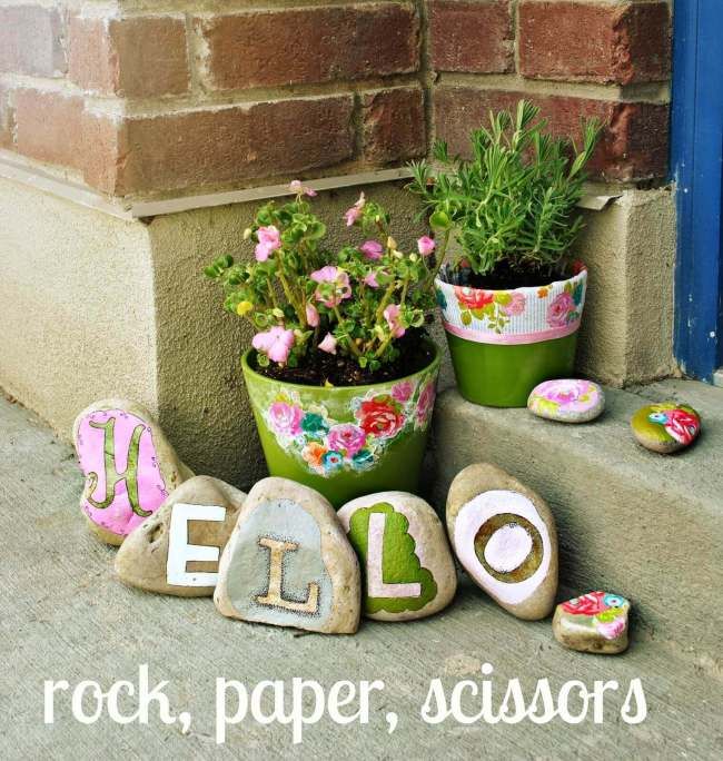 some rocks are sitting on the steps with flowers and letters that spell out hello rock, paper scissors