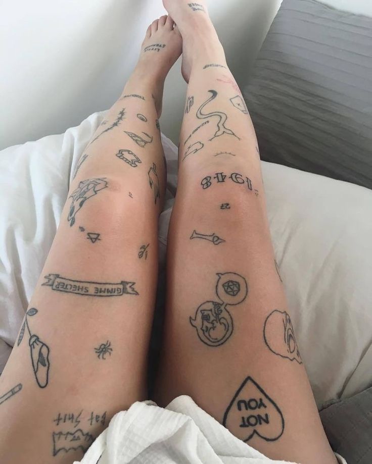 two people with tattoos on their legs laying in bed