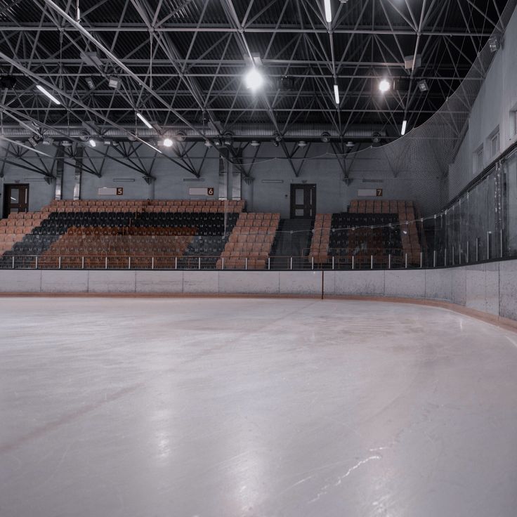 an empty ice rink with seats and lights