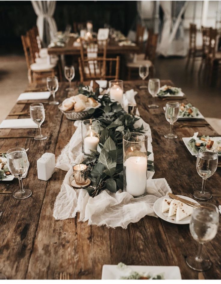 a wooden table topped with lots of plates and candles