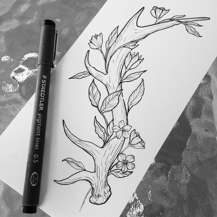 a black and white drawing of a tree with flowers on it next to a marker