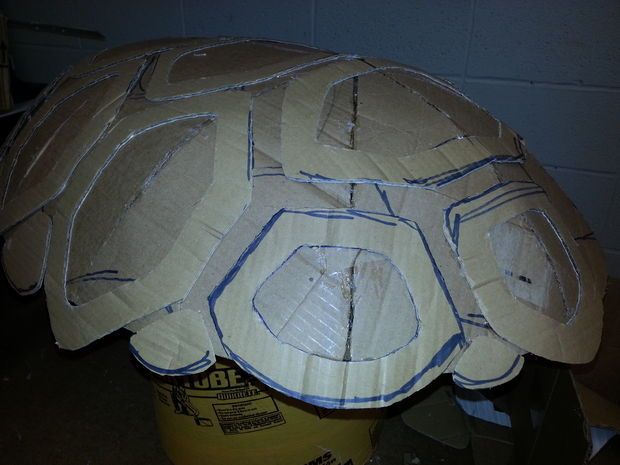 a cardboard turtle is sitting on top of a yellow barrel