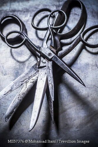 an old pair of scissors sitting on top of a metal table next to another pair of scissors