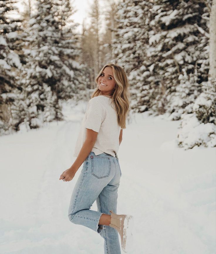 a woman standing in the snow with trees behind her