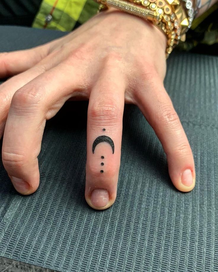 a woman's hand with a small crescent moon tattoo on her left index finger