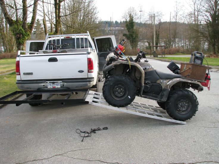 a white truck pulling a atv on a trailer