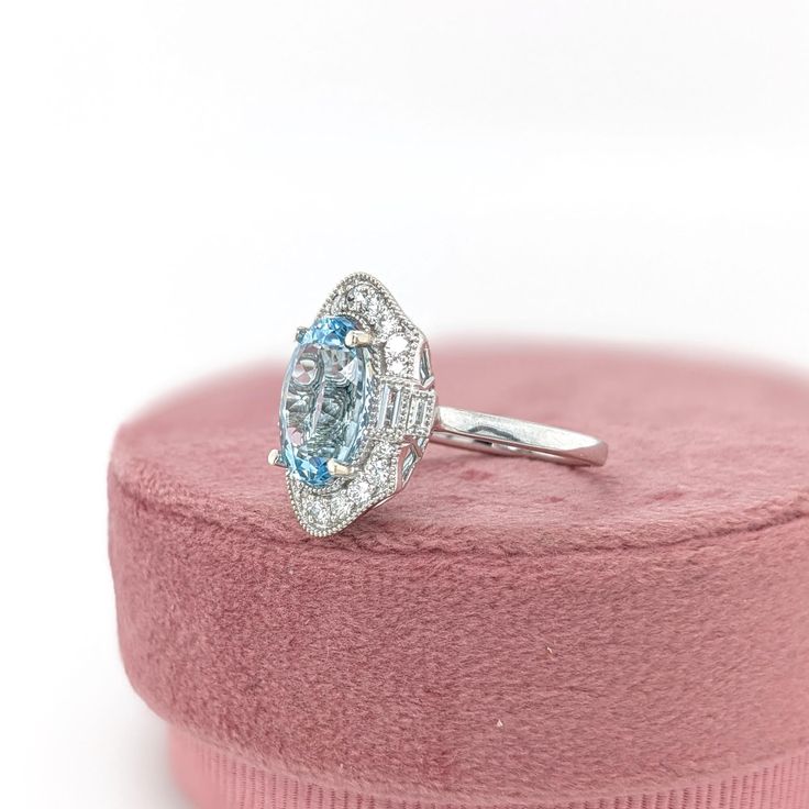 This beautiful ring features a 4.39 carat Aquamarine gemstone with natural earth mined diamonds and milgrain detail, set in solid 14K gold. This Aquamarine ring makes a lovely March birthstone gift for your loved ones! This ring is made with solid 14K Gold and natural Earth mined SI / G-H diamonds. As listed, this ring is ready to ship. If you're interested in purchasing this setting with a different center stone please message us! Oval Topaz Ring In Platinum, Oval Platinum Halo Ring As Gift, Art Deco Oval Topaz Ring With Center Stone, Art Deco Oval Diamond Ring With Accent Stones, Gia Certified Oval Topaz Ring For Gift, Gia Certified Oval Topaz Ring As Gift, Heirloom Oval Topaz Ring With Halo Setting, Designer Silver Jewellery, Jewelry Showcases