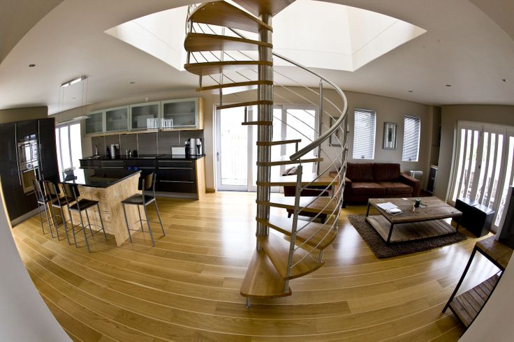 a living room filled with furniture and a spiral staircase in front of a kitchen area