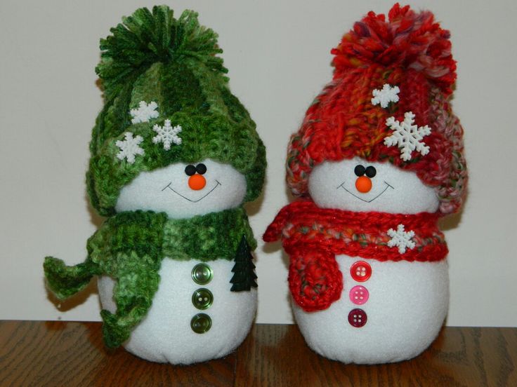 two snowmen wearing hats and scarves on top of a wooden table