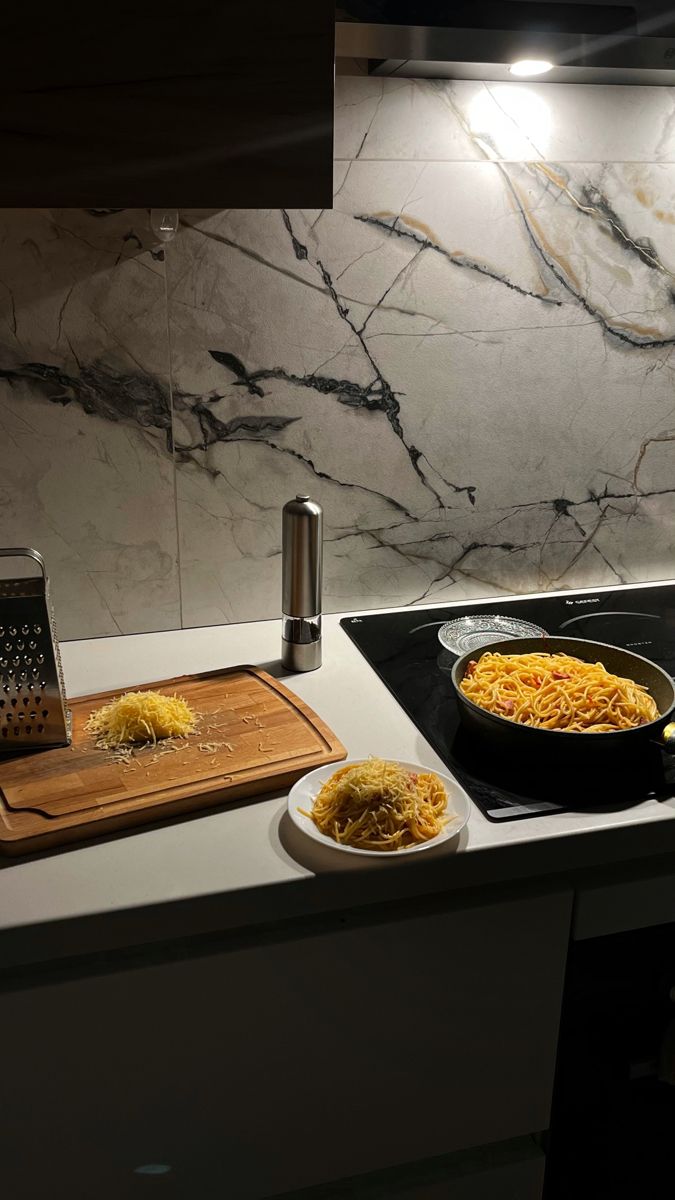 a stove top with some food on it next to a cutting board and grater