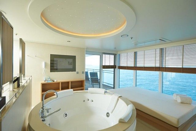 a large white bath tub sitting in the middle of a bathroom next to a window