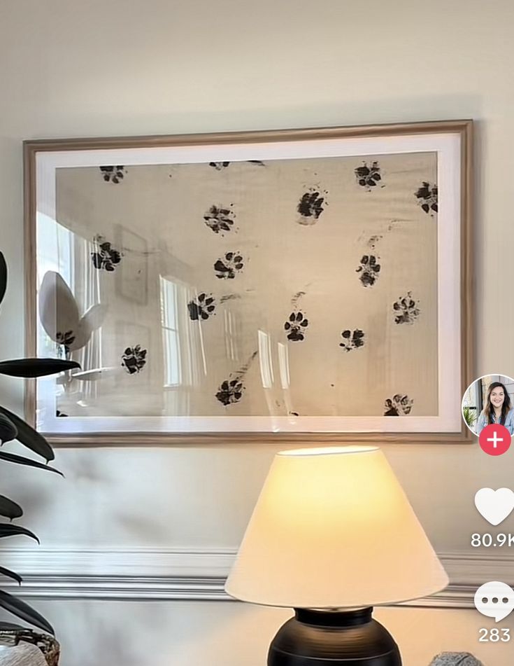 a lamp sitting on top of a wooden table next to a framed photo and potted plant