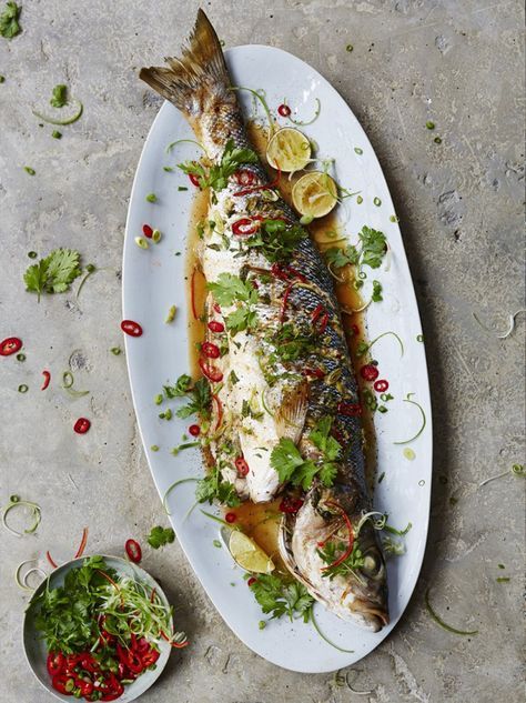 a fish on a plate next to a bowl of salad