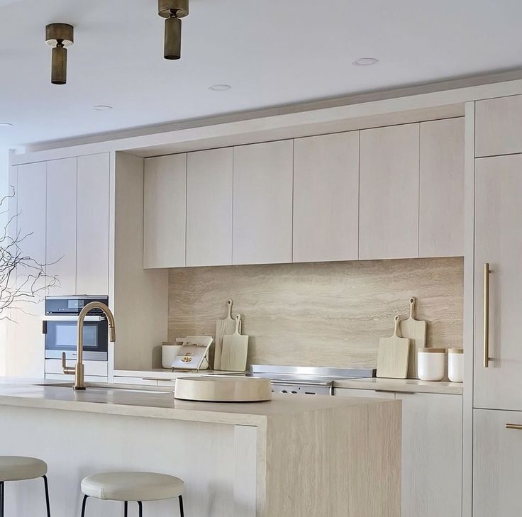 a kitchen with white cabinets and stools next to a counter top that has two vases on it