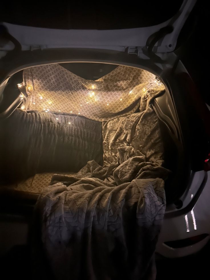 an open car trunk with some lights in the back and blankets on it's sides