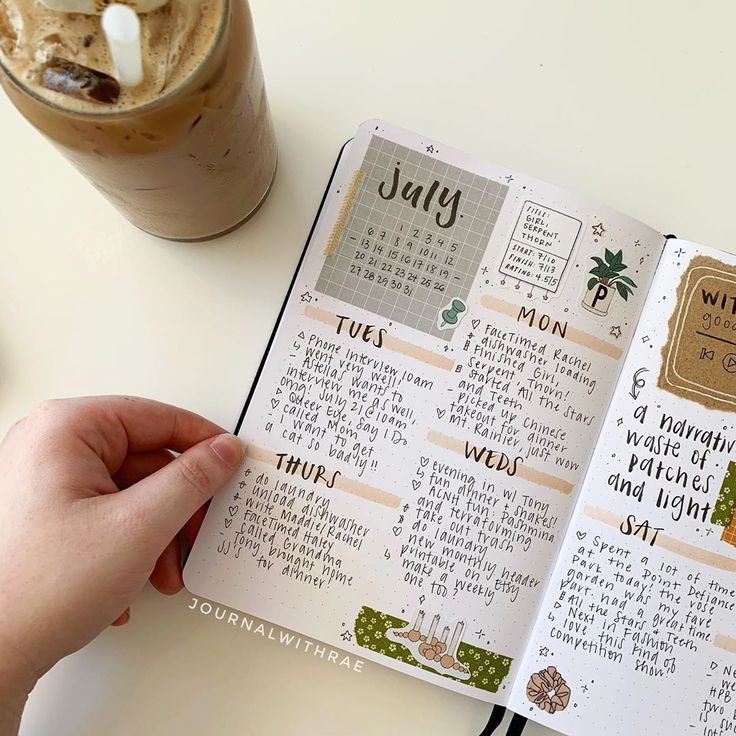 a person is holding an open planner with coffee and milk in the background on a table