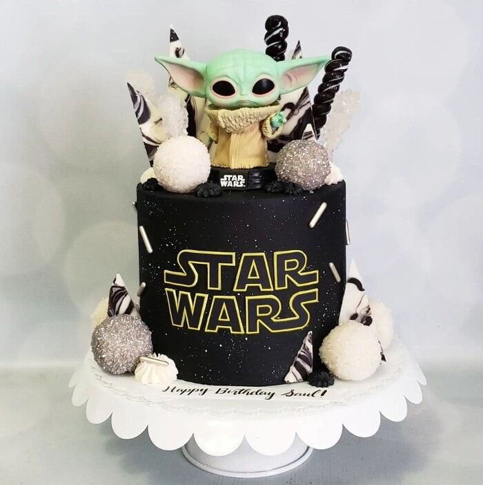 a star wars themed birthday cake with the baby yoda on top and decorations around it