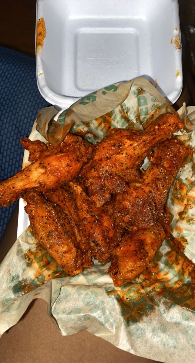 chicken wings in a take out box on a table