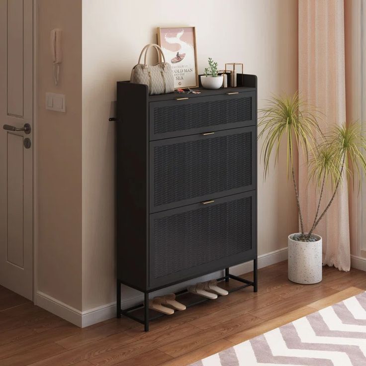 a black cabinet with two drawers and a potted plant next to it on a wooden floor